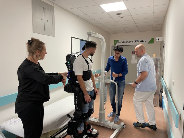 Patient using robotic exoskeleton with medical staff assistance