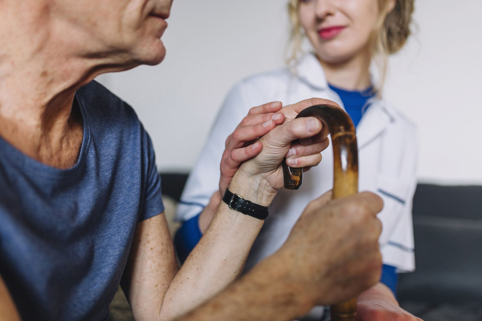 Caregiver assisting elderly person holding a cane
