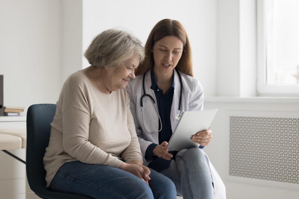 Doctor reviewing tablet results with elderly patient