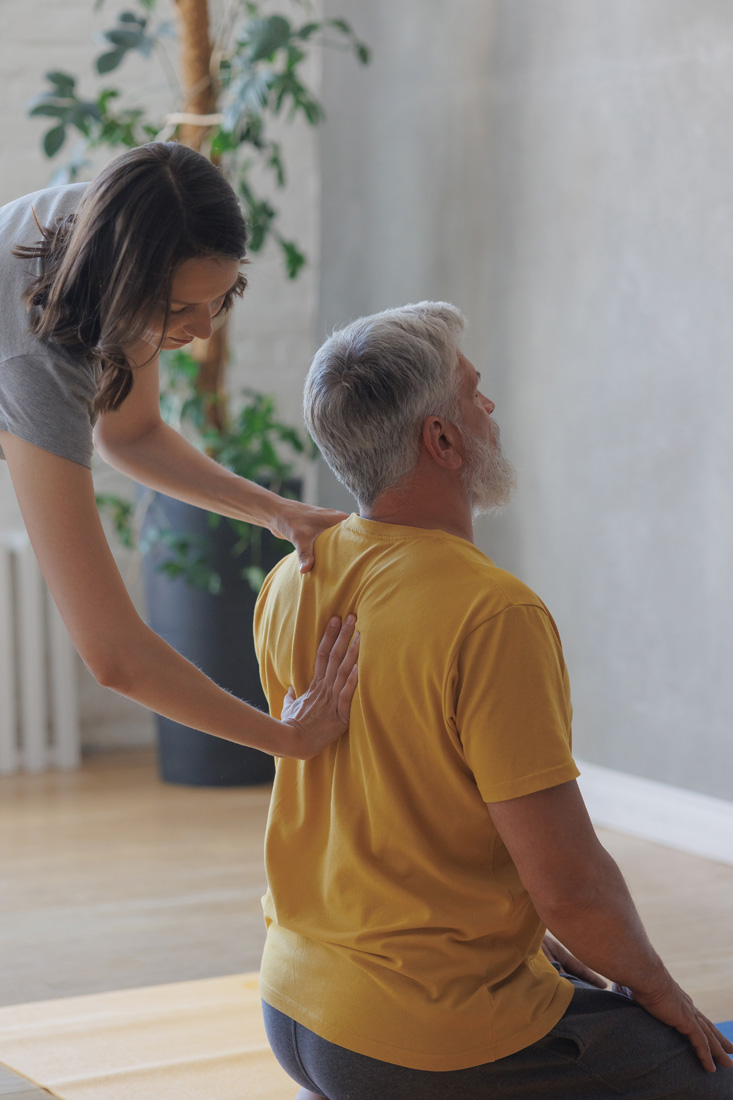 Therapist assisting senior man with back exercise