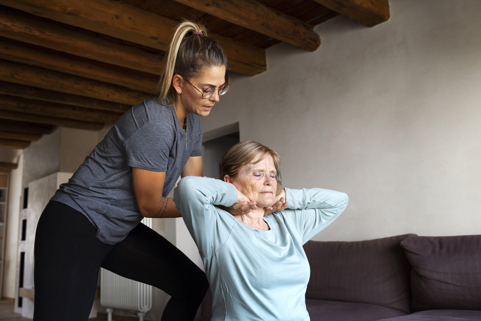 Personal trainer assisting senior woman with neck stretch