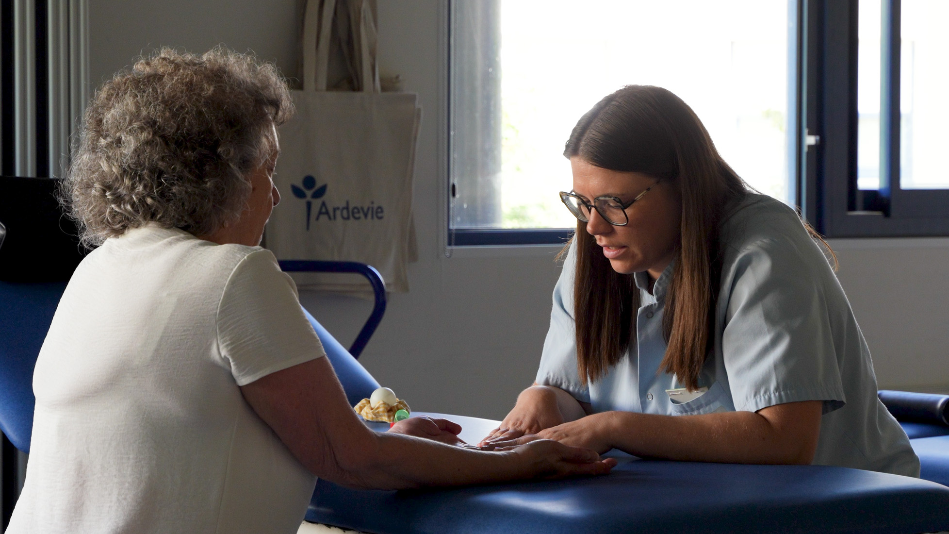 Therapist assisting elderly woman with hand therapy