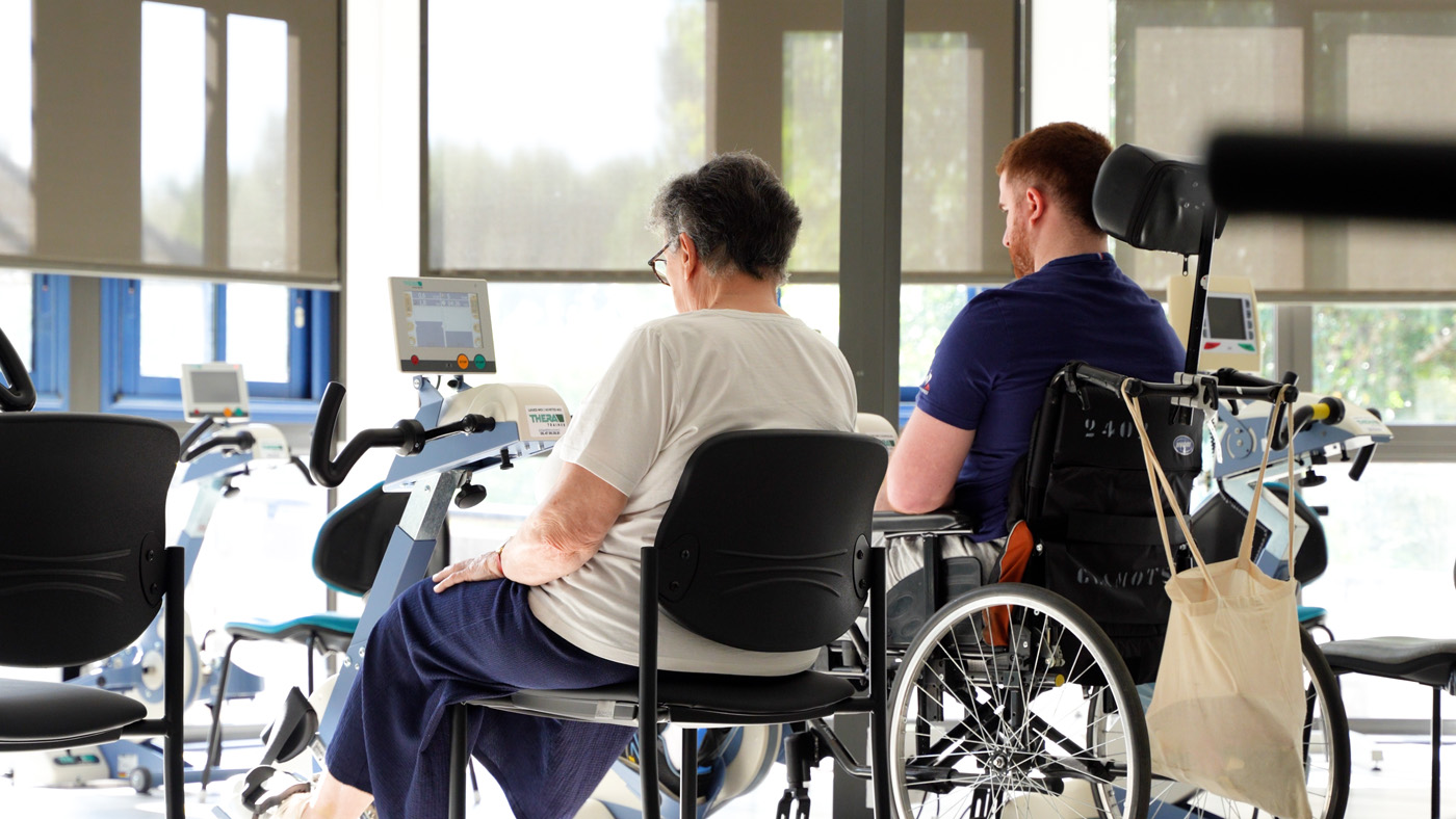 Two people using arm exercise machines in rehab