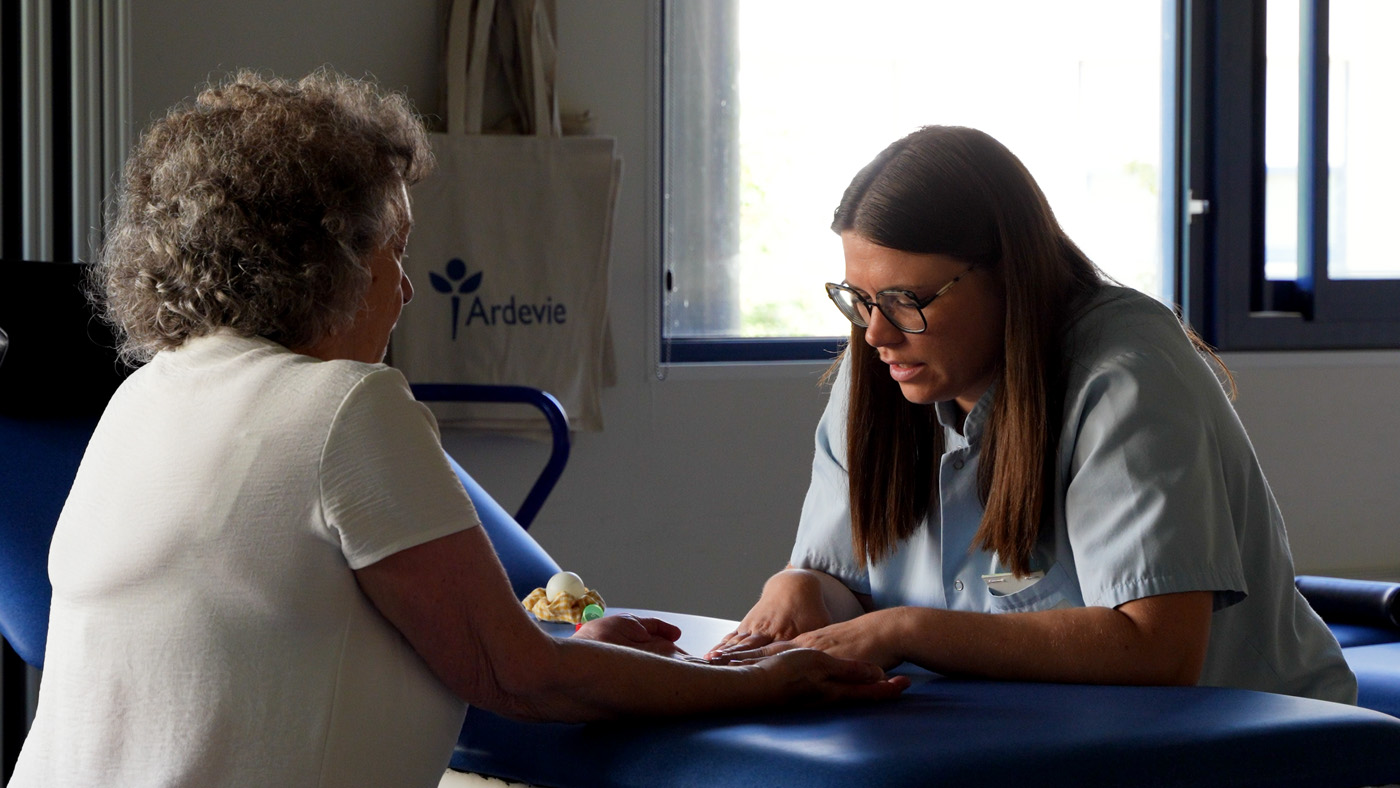 Healthcare worker examining elderly woman's hand