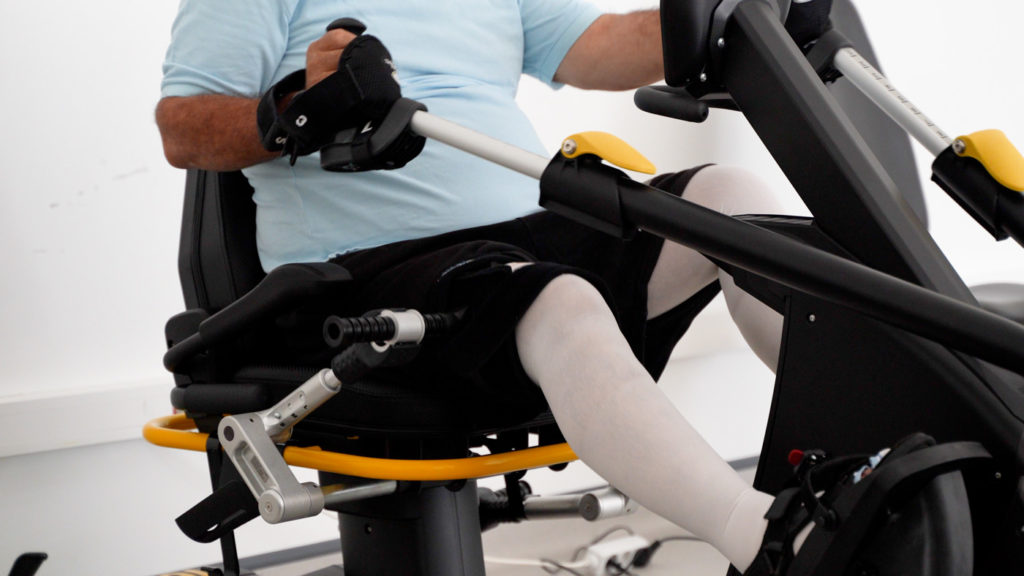 Person using seated rehabilitation exercise machine indoors