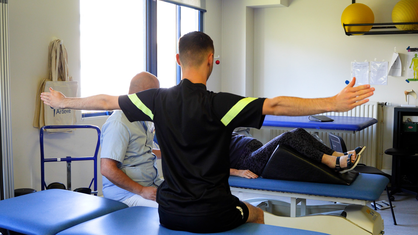 Physical therapist guiding patient arm exercise in clinic