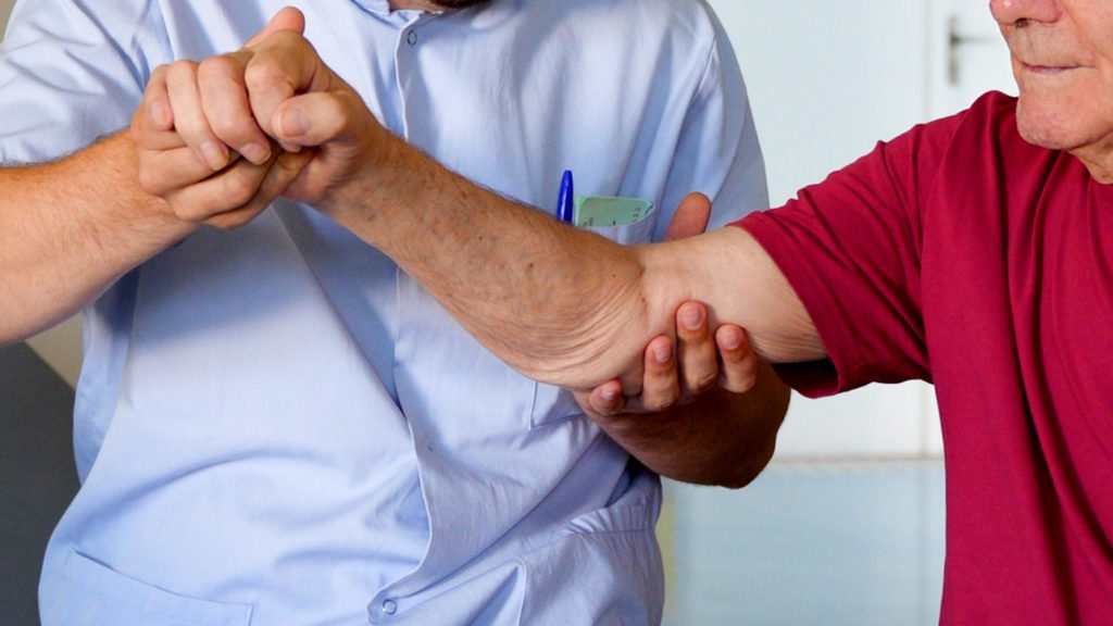 Healthcare worker assisting elderly patient with arm exercise